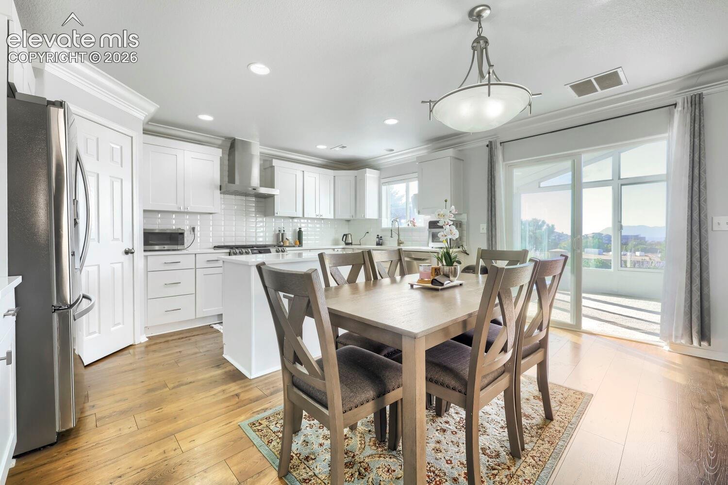 Kitchen featuring white cabinetry, subway tile backsplash, stainless steel appliances, central island, and wood-finish flooring