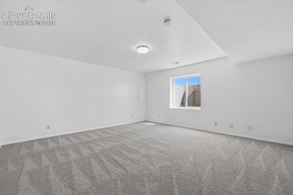 Interior space featuring neutral wall tones, wall-to-wall carpeting, a flush-mount ceiling light, and an egress window with a window well