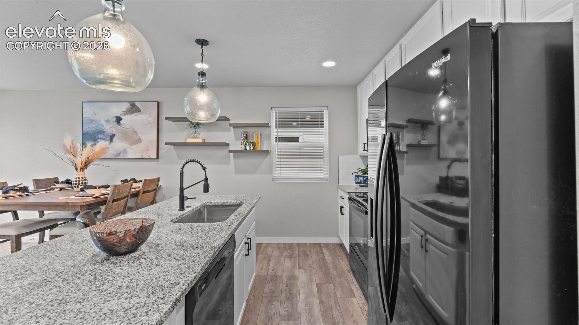 Kitchen featuring white cabinetry, stone-finish countertops, wood-finish flooring, floating wall shelves, and matte black plumbing fixtures