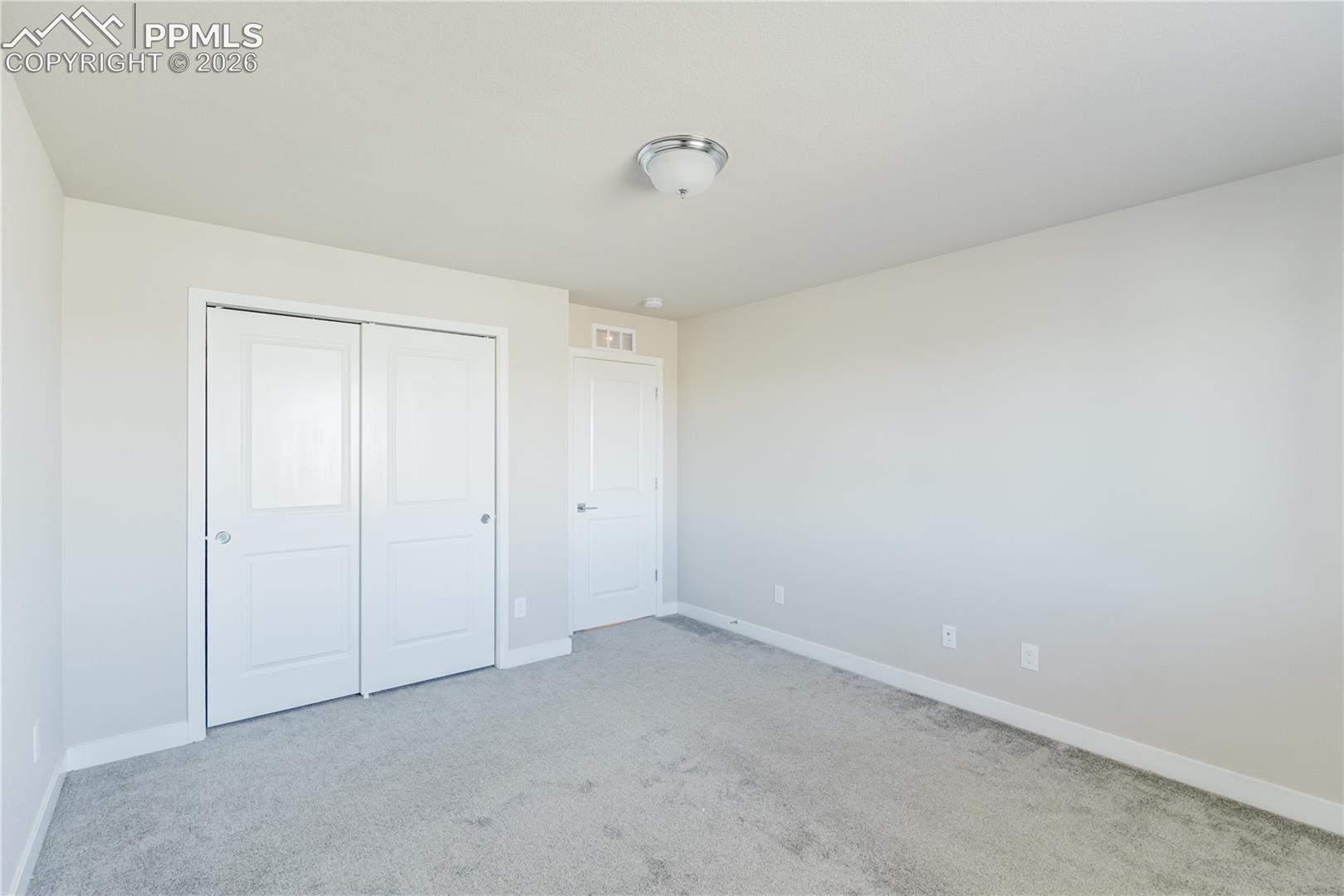 Unfurnished bedroom featuring light carpet and a closet
