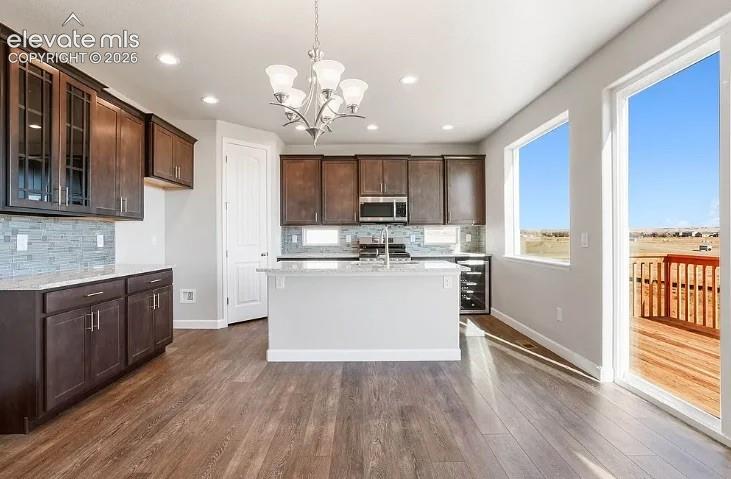 Kitchen featuring wood cabinetry, stone-surface countertops, tile backsplash, recessed lighting, and wood-finish flooring