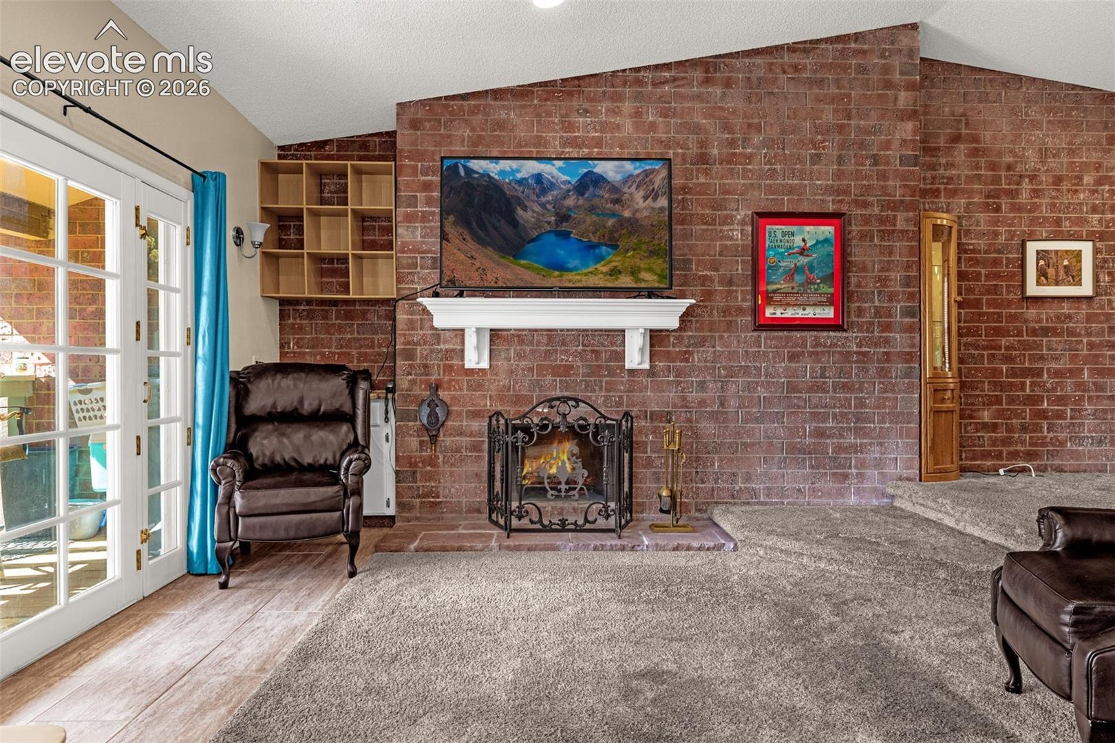 Floor-to-ceiling brick fireplace featuring a wood-burning hearth, custom mantel, and built-in shelving, complemented by a multi-pane glass door leading to exterior space