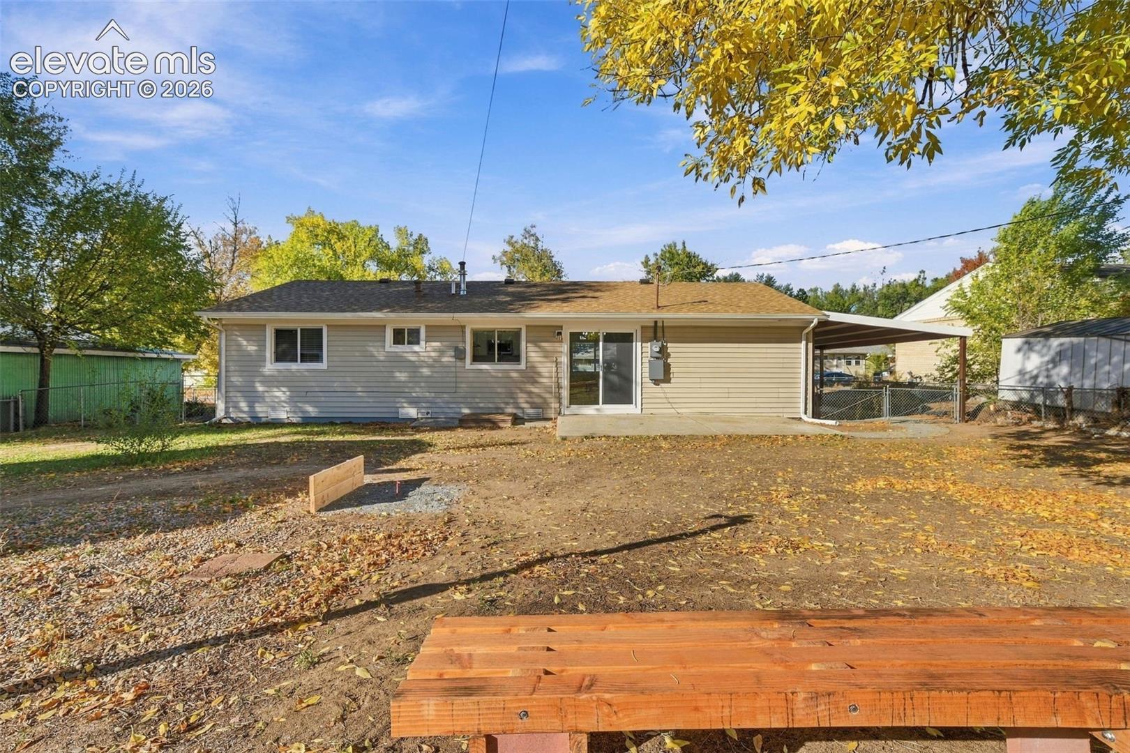 Rear exterior featuring light-colored horizontal siding, a concrete patio, and an attached carport