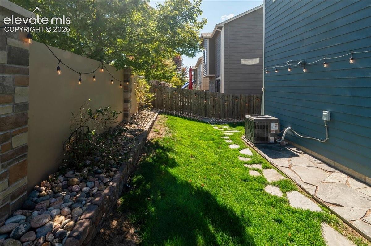 Expansive side yard featuring a manicured lawn, flagstone pathway, and stone-clad retaining wall