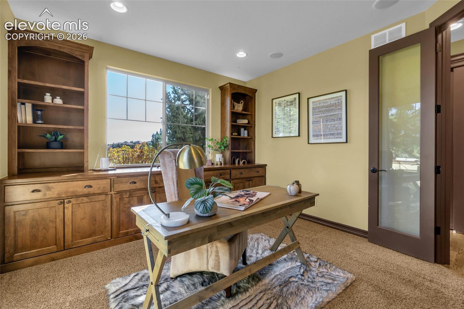 Built-in wooden cabinetry with shelving, recessed lighting, and a glass-panel door