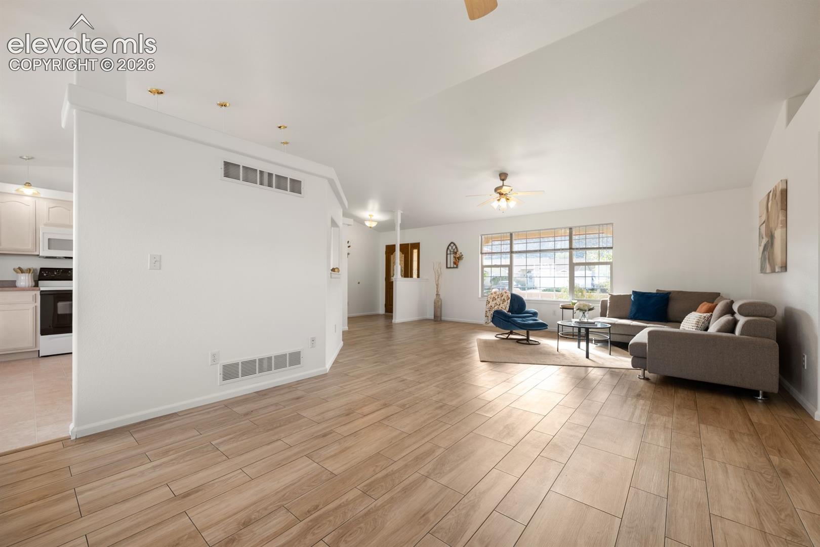 Open-concept floor plan featuring wood-finish flooring, recessed lighting, ceiling fans, and large windows