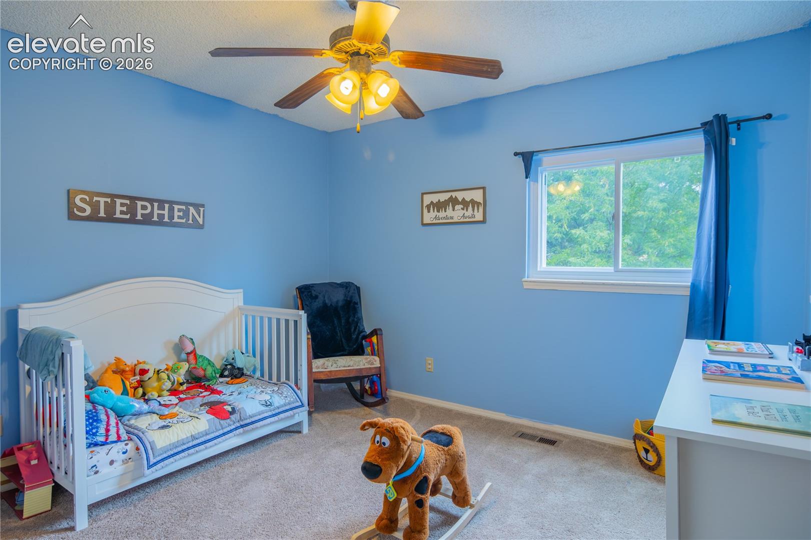Carpeted room featuring a ceiling fan with integrated lighting, a window with a white frame, and blue wall paint
