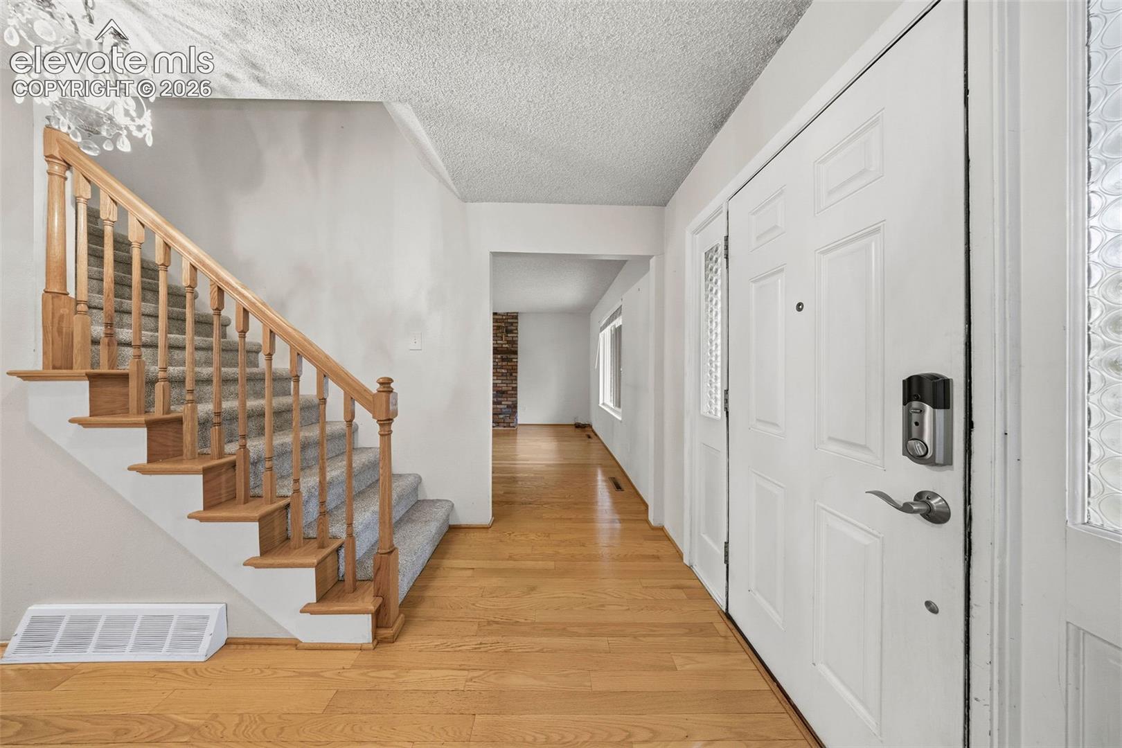 Foyer featuring wood-finish flooring, staircase with a wood railing, and an entry door with glass paneling