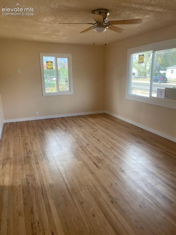 Interior space featuring wood flooring, sliding windows, fresh paint, and a ceiling fan with integrated lighting