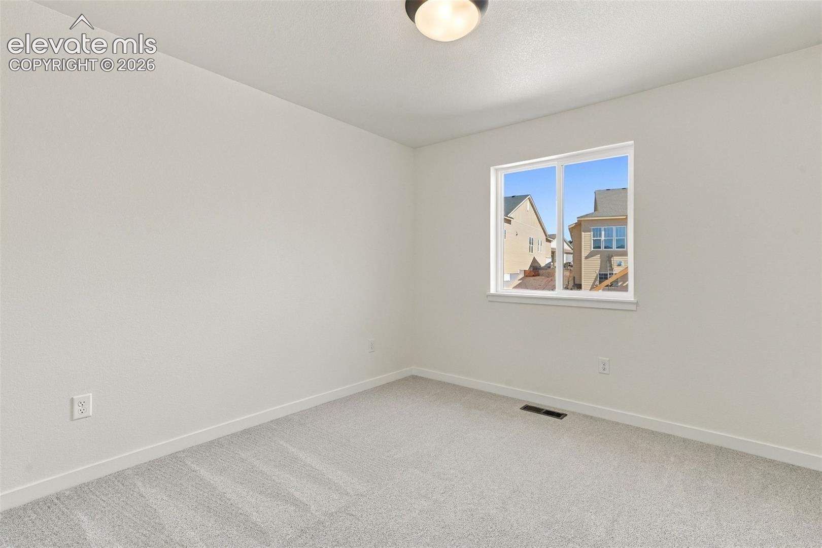 Bedroom 2 features with soft white walls and plush gray carpeting