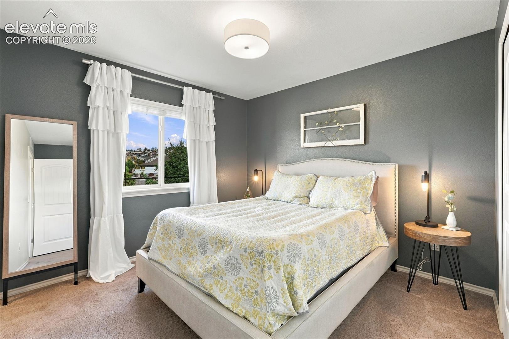 Neutral-toned interior space featuring a double-paned window with exterior landscape, a drum-style flush mount ceiling light, and a multi-panel interior door