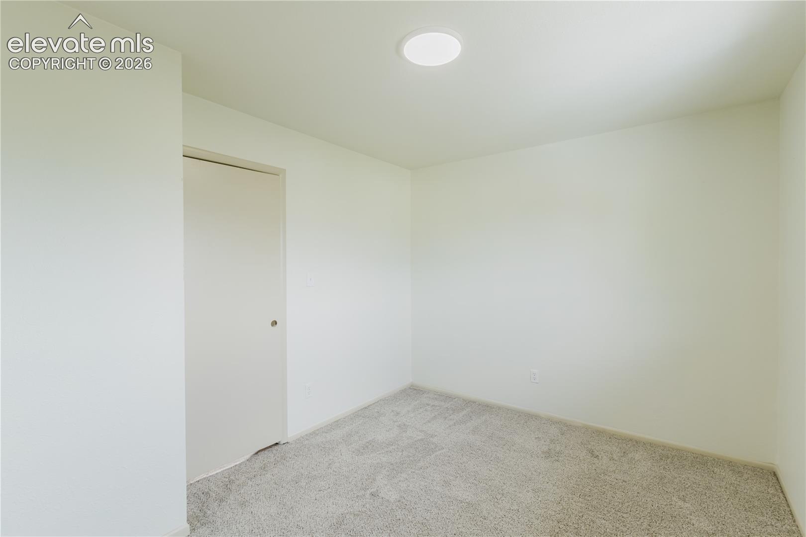 Neutral tone wall paint, light-colored carpet, and a flush-mount ceiling light fixture