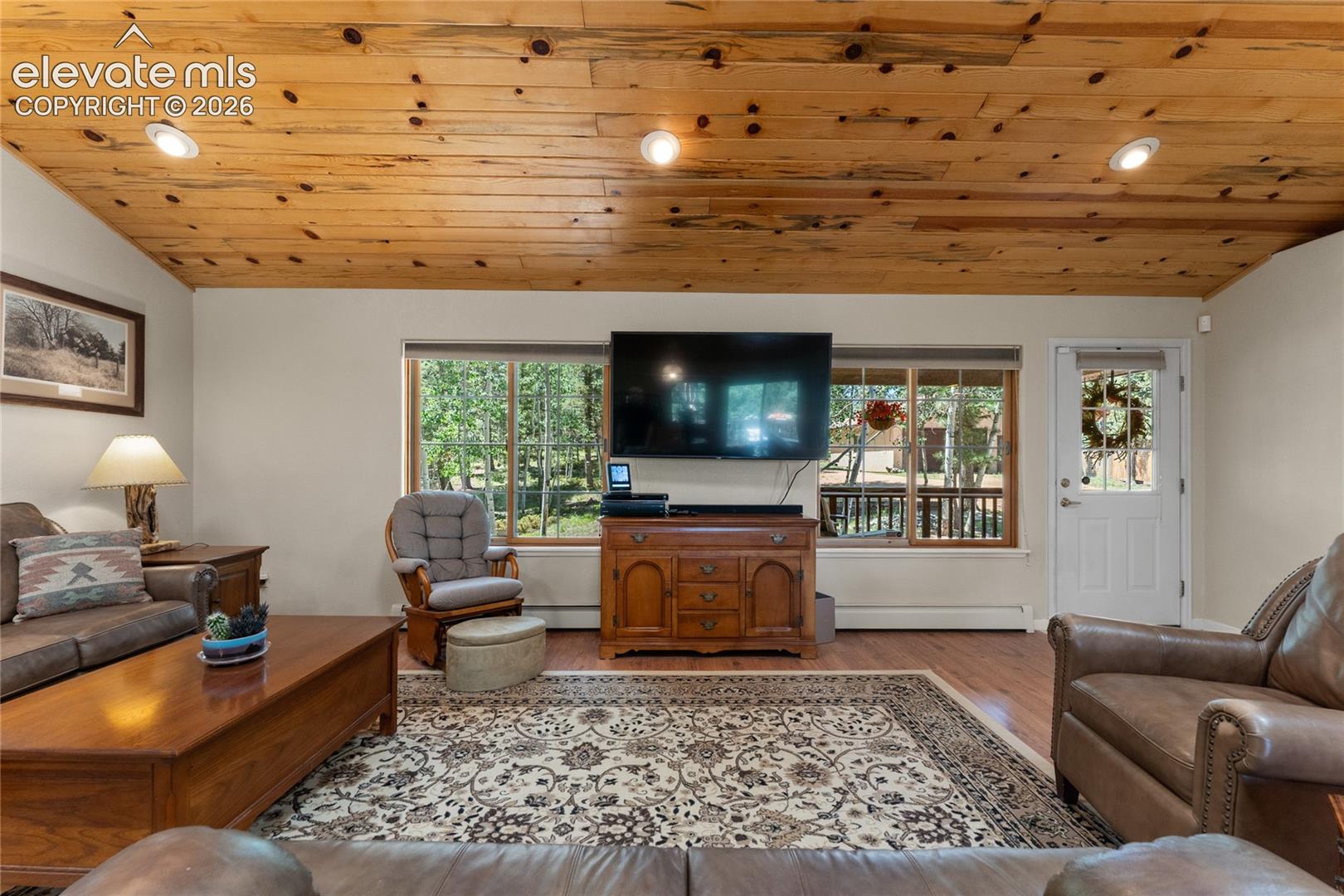 Living area featuring a knotty pine ceiling with recessed lighting, wood-finish flooring, and expansive windows