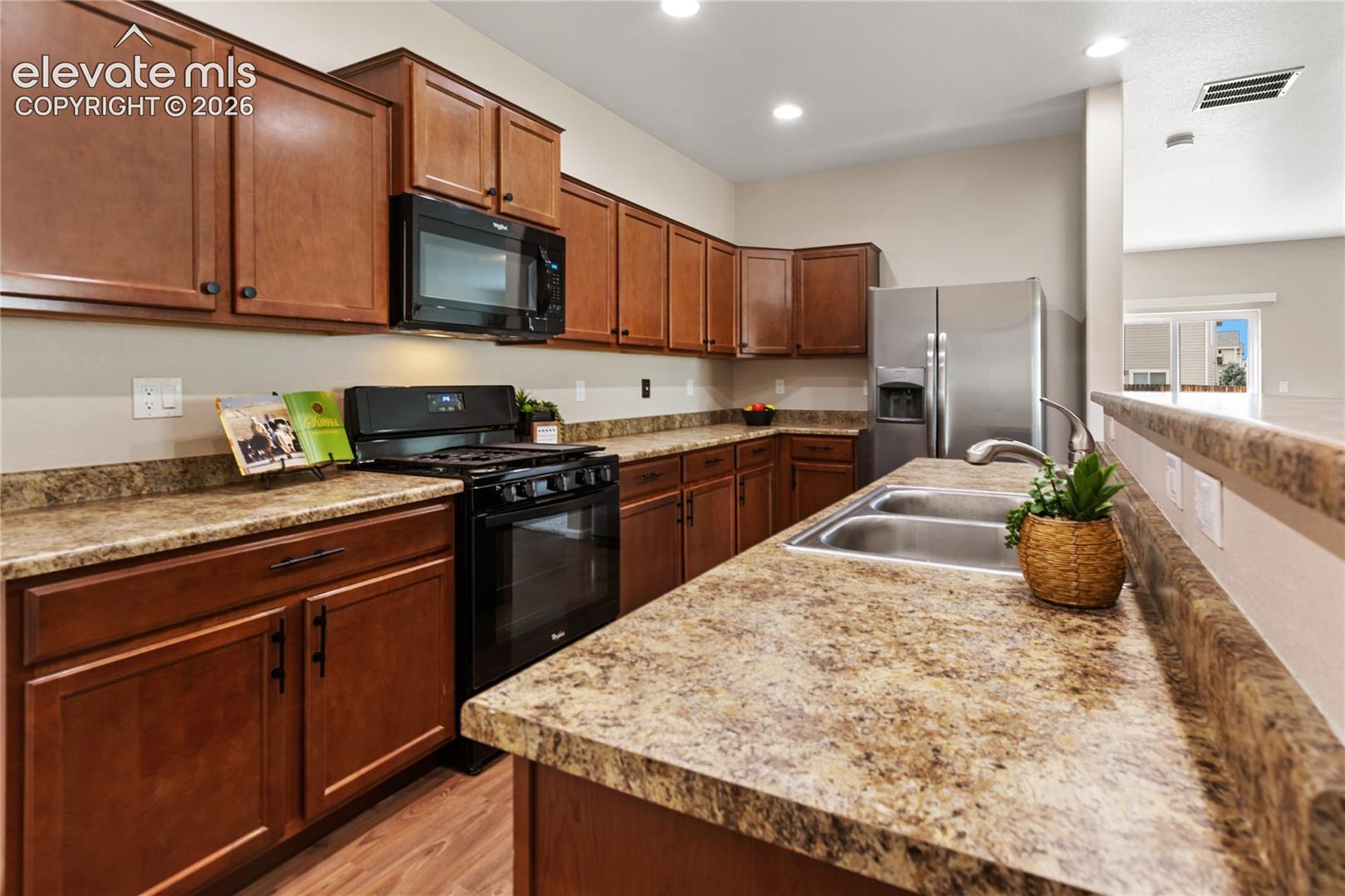 Kitchen features gas range/oven, stainless steel refrigerator and a kitchen island with additional places for seating