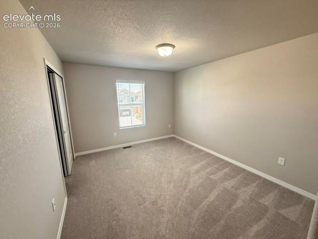 Neutral-toned carpeting, single window with blinds, overhead flush mount lighting, light-colored walls, and a bi-fold closet door