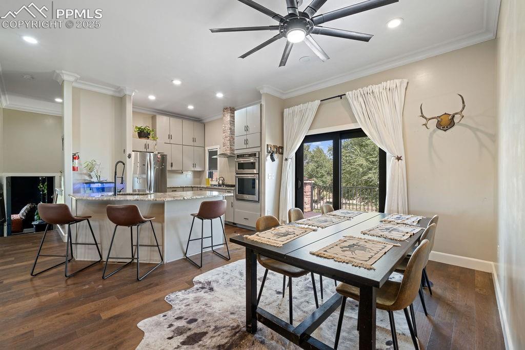 Dining space with crown molding, dark wood-style flooring, a ceiling fan, and recessed lighting