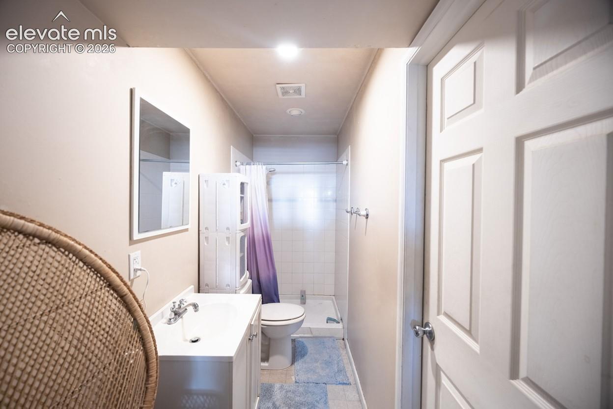 White paneled interior door, vanity with integrated sink, wall-mounted mirror, recessed lighting, and shower with glass enclosure