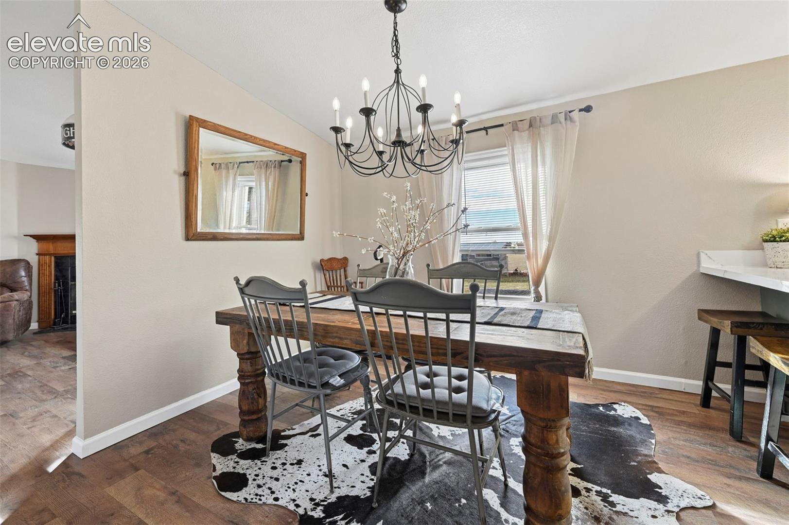 Dining area featuring wood-finish flooring, a decorative metal chandelier, and stone-surface countertop