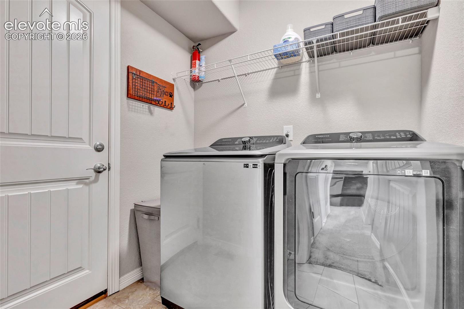 Dedicated utility space featuring a paneled interior door, light-toned wall paint, and overhead wire shelving