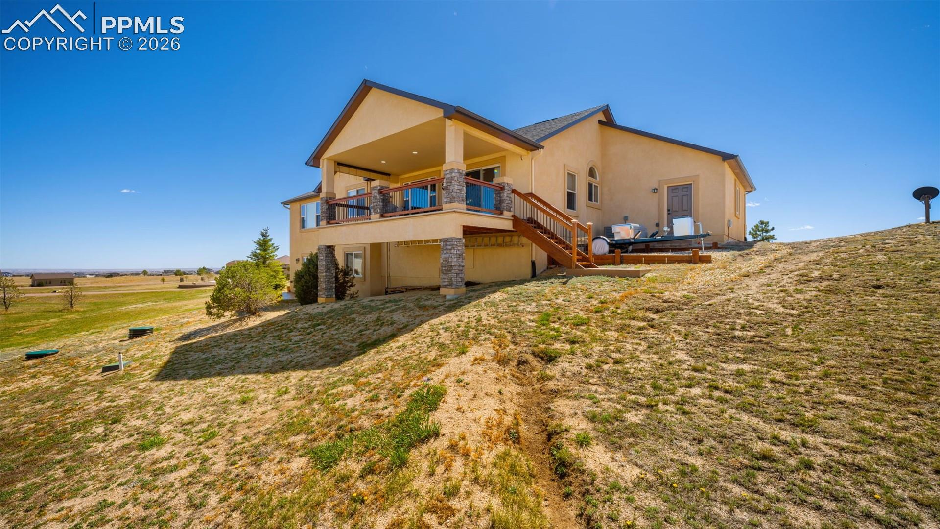 Rear view of property with stucco siding, deck, and yard