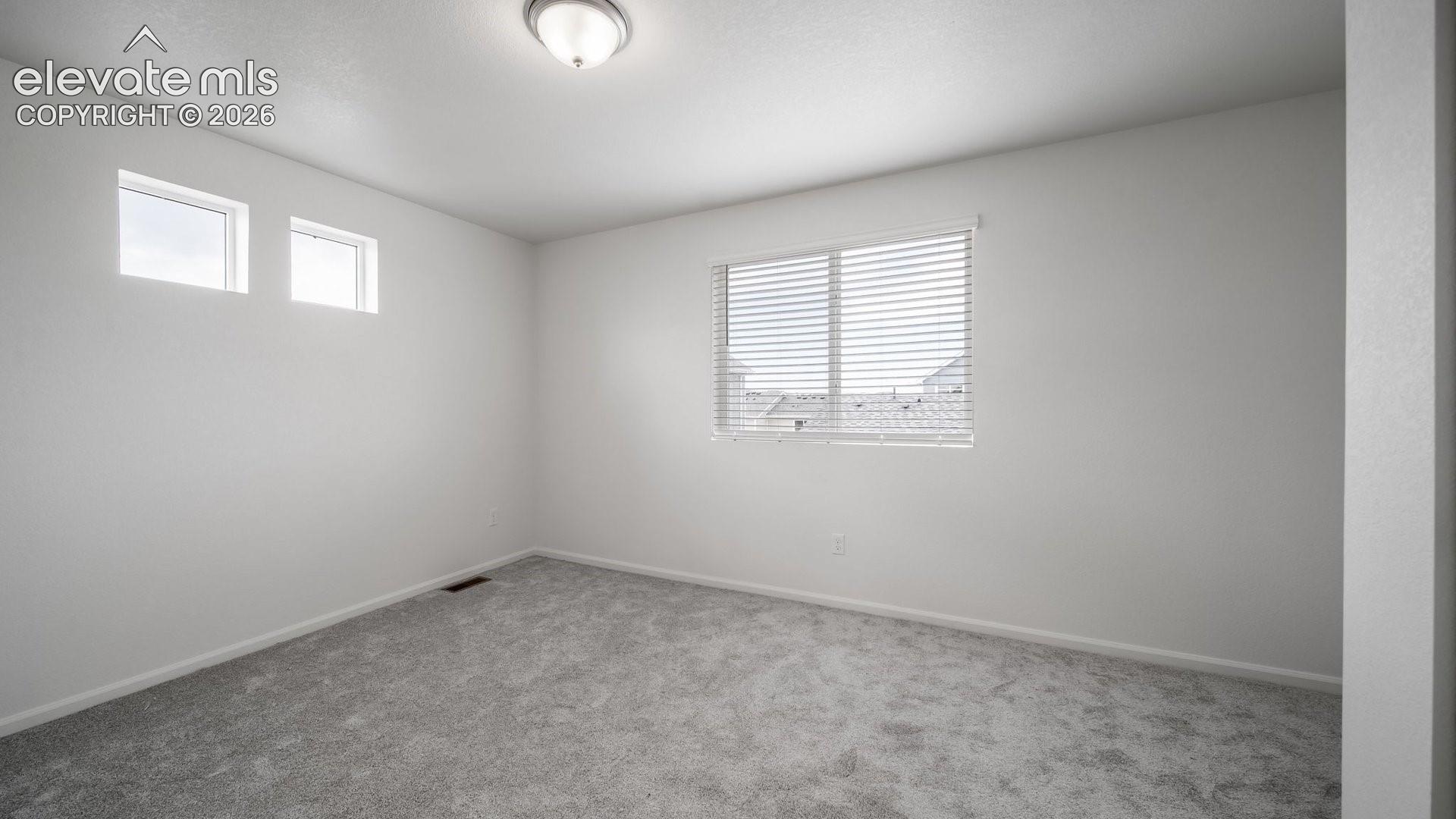 Recessed lighting, large window with blinds, two transom windows, light gray wall paint, and gray carpeted flooring
*photos of a model home*