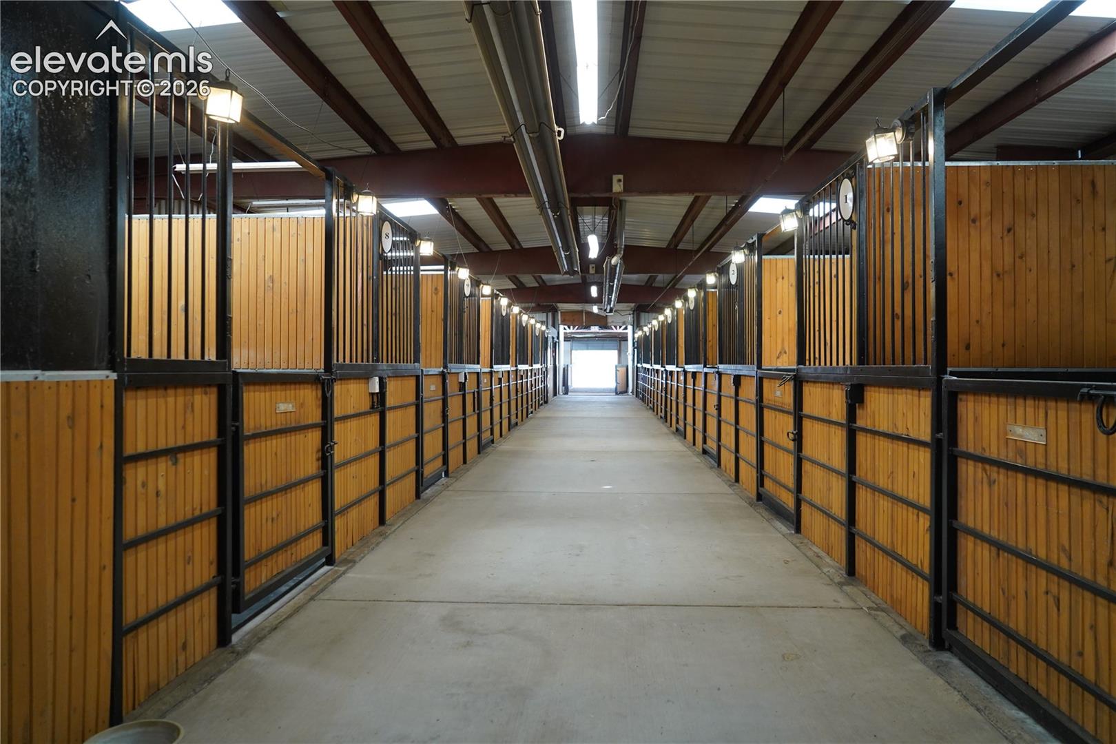 Indoor facility featuring multiple stalls with wood paneling and black metal gating