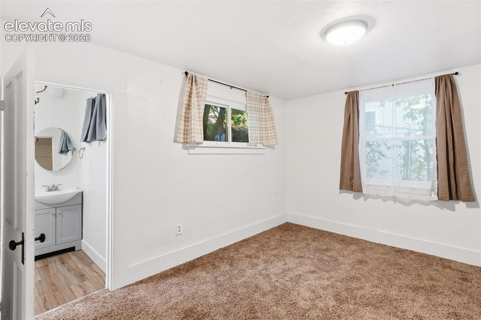 Neutral-toned room featuring carpeted flooring and two windows with double-pane glass