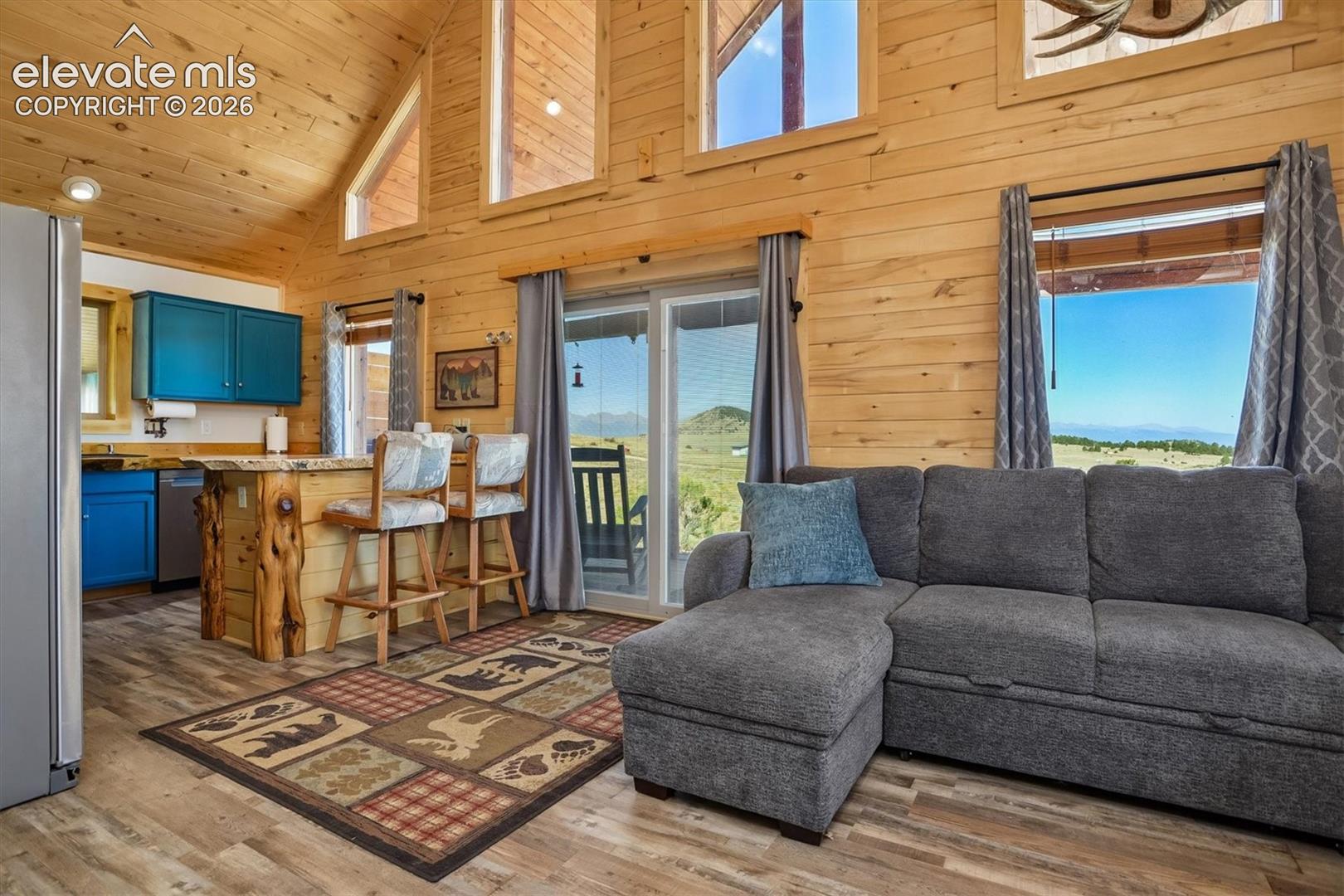 Open concept living area featuring wood-finish walls and vaulted ceilings with upper-level windows