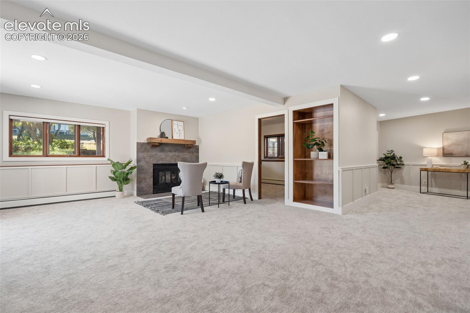 Recessed lighting, built-in shelving, fireplace with stone surround, wainscoting, and built-in window seating