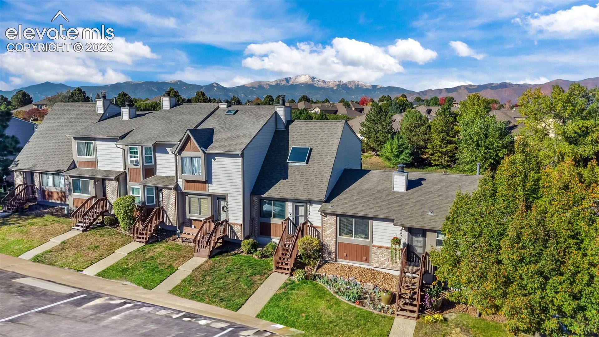 Multi-unit residential exterior featuring horizontal siding, brick masonry detailing, shingled roofing, skylights, and individual wooden stair entryways