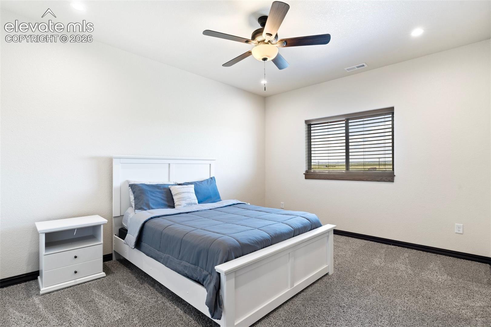 Carpeted room featuring a ceiling fan with integrated lighting, recessed lighting, and a window with blinds