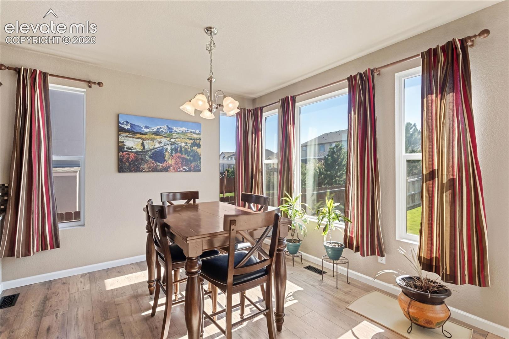 Dining area featuring wood-finish flooring, a multi-light chandelier, and large windows with natural lighting