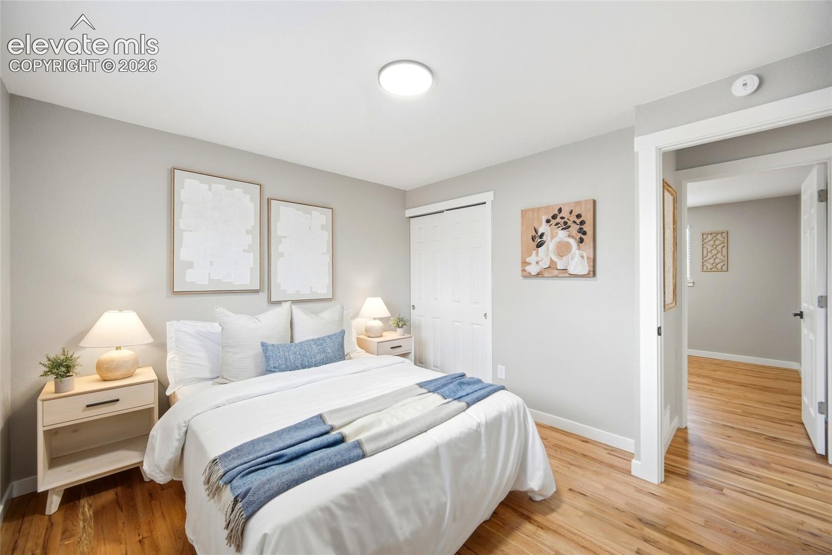 Hardwood flooring, light gray wall finishes, white trim, and a built-in closet with bi-fold doors
