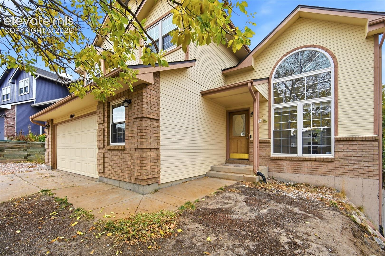 Exterior featuring horizontal siding, brick veneer foundation, arched multi-pane window, and attached garage