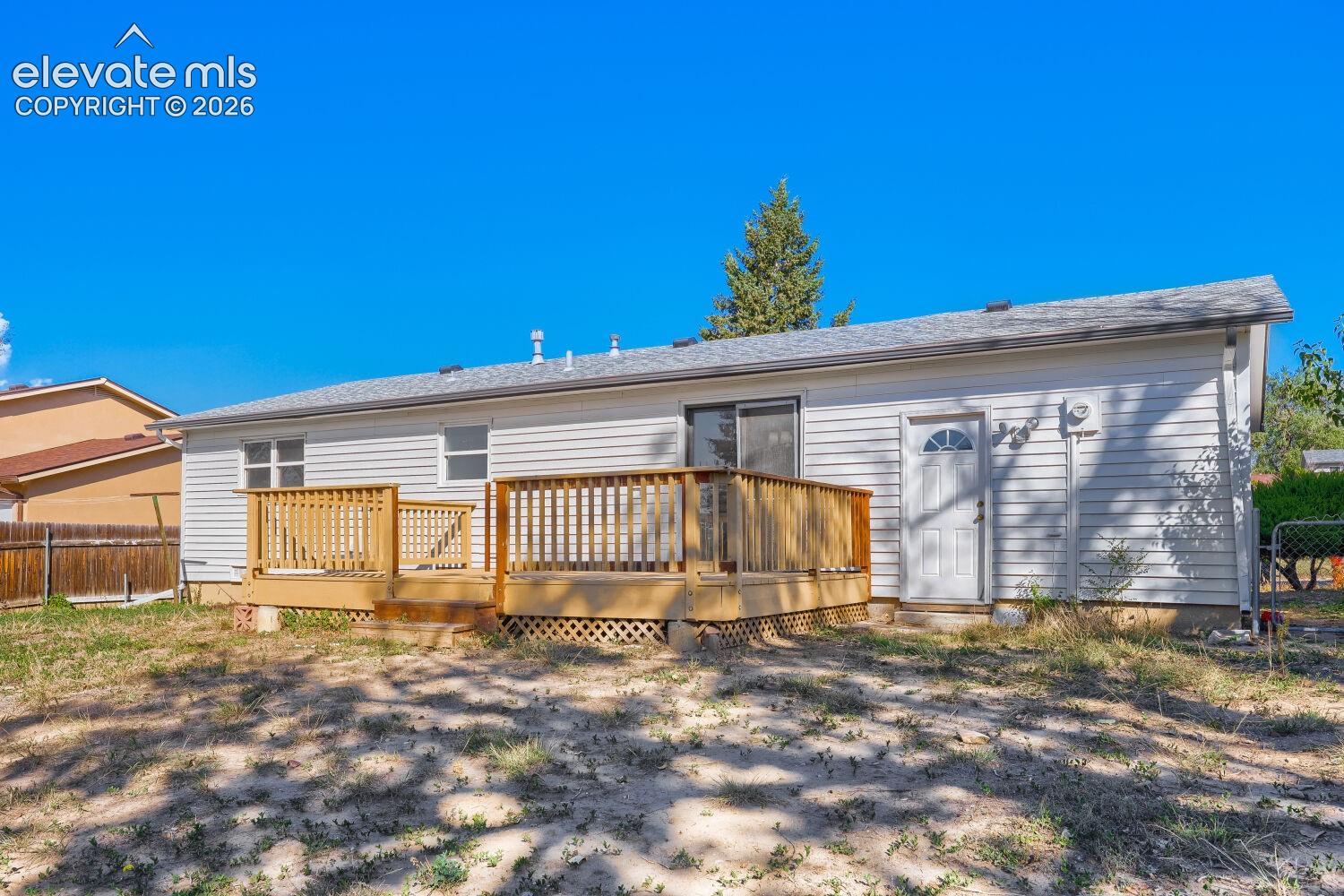 Charming single-story home featuring a spacious wooden deck with railings, ideal for outdoor entertaining