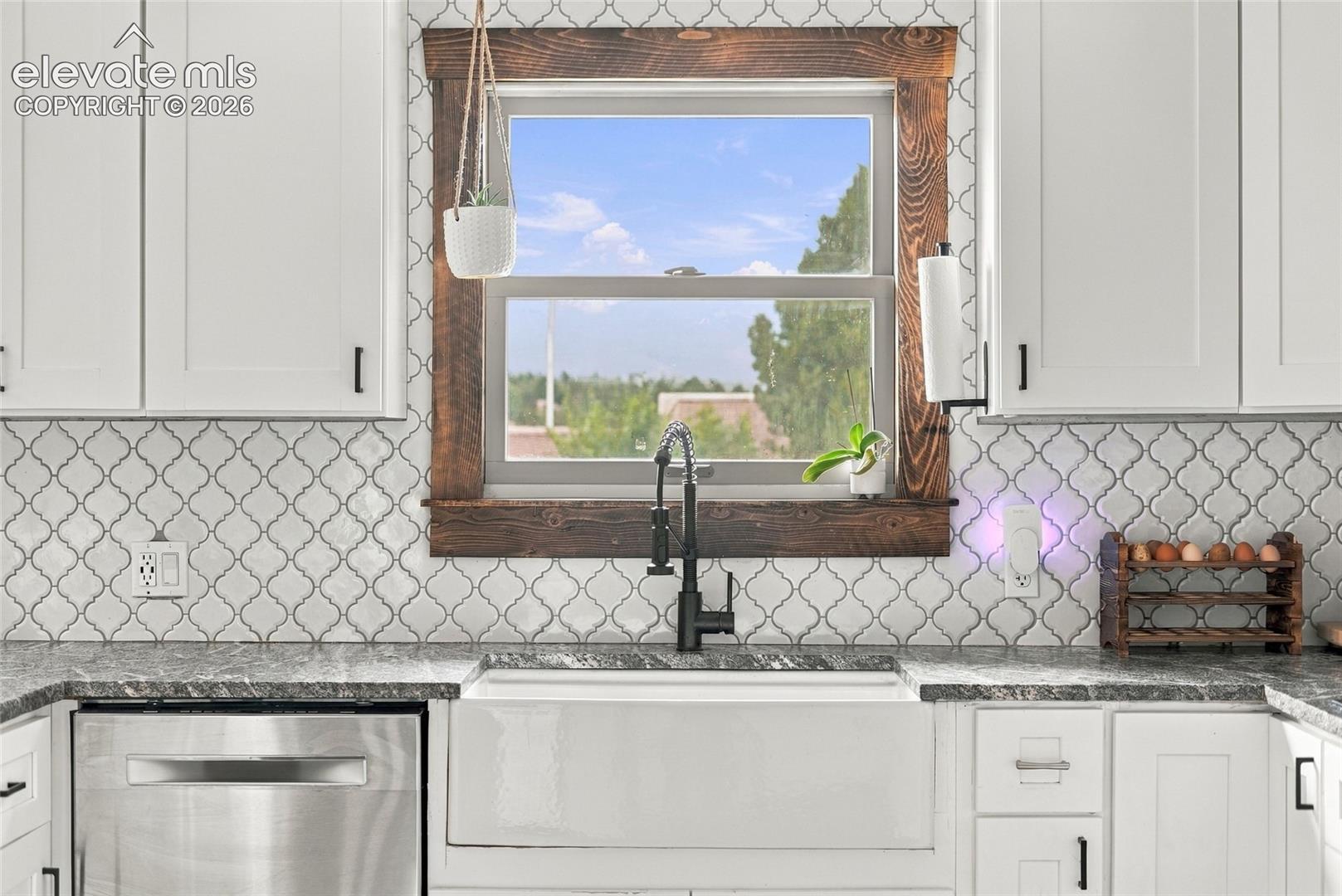 White shaker cabinetry with matte black hardware, arabesque tile backsplash, and a farmhouse sink with a black gooseneck faucet