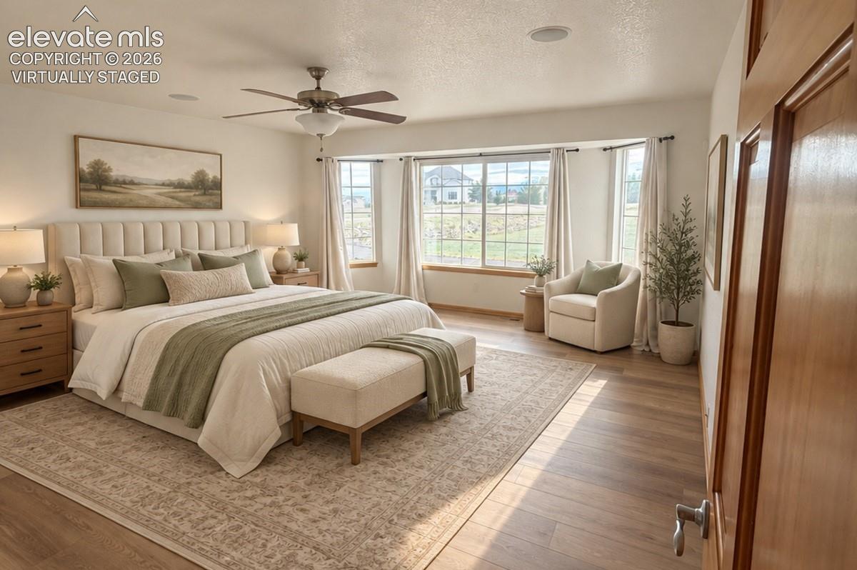 Expansive main-level primary room featuring wood-finish flooring, a ceiling fan with integrated lighting, and multiple windows. Virtually staged.