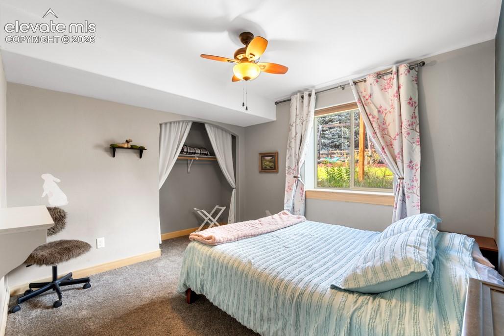 Recessed closet with a clothing rod, ceiling fan with integrated lighting, wood-finish window trim, and wall-mounted shelving