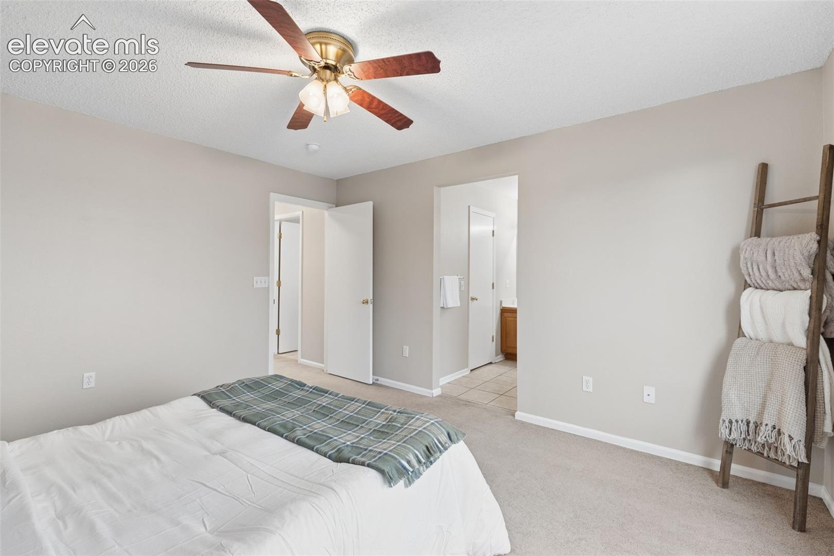 Neutral-toned interior space featuring a brass-finish ceiling fan with wood-toned blades and wall-to-wall carpeting