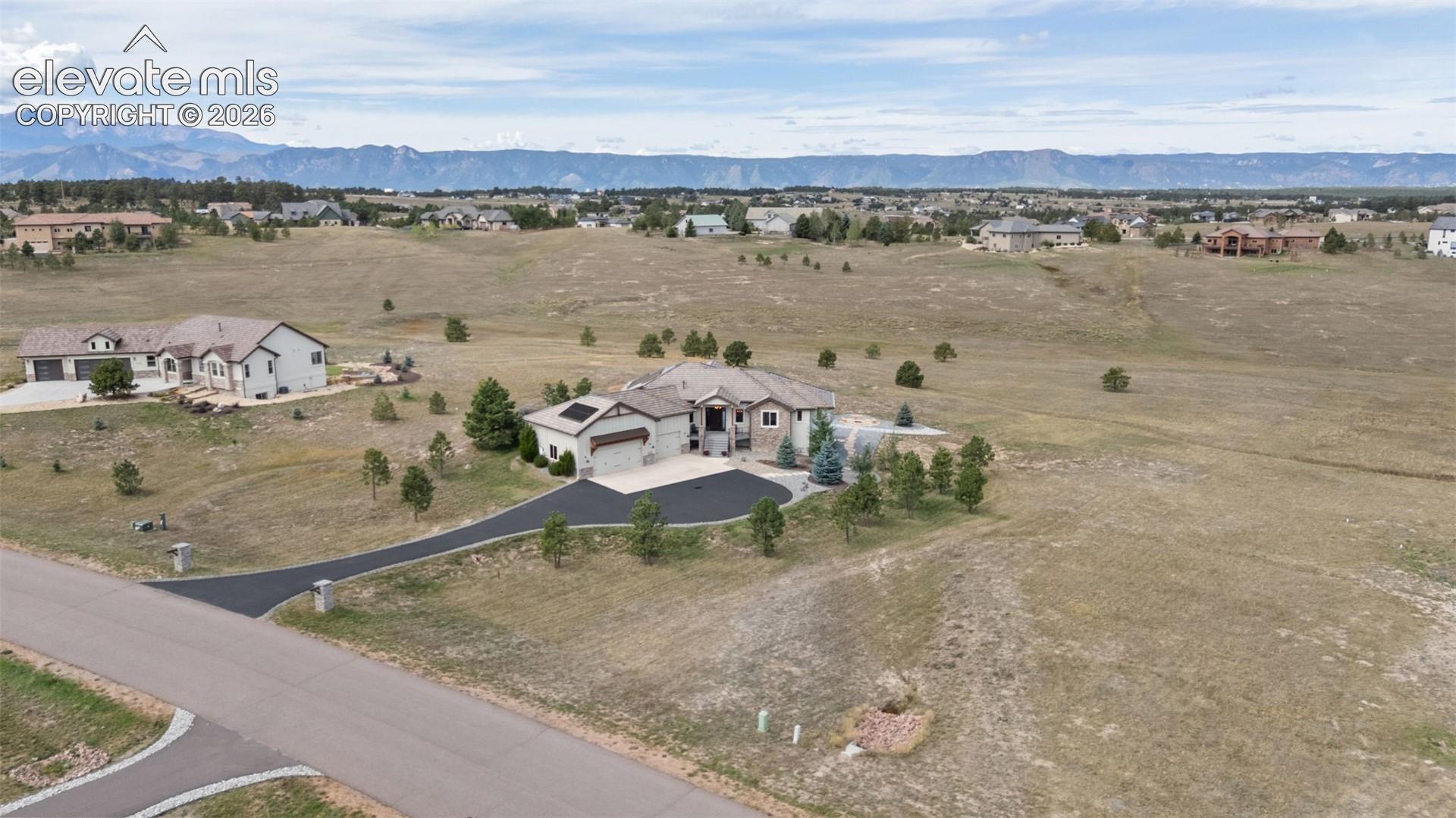 Expansive property featuring a paved driveway, attached garage, and mountain scenery