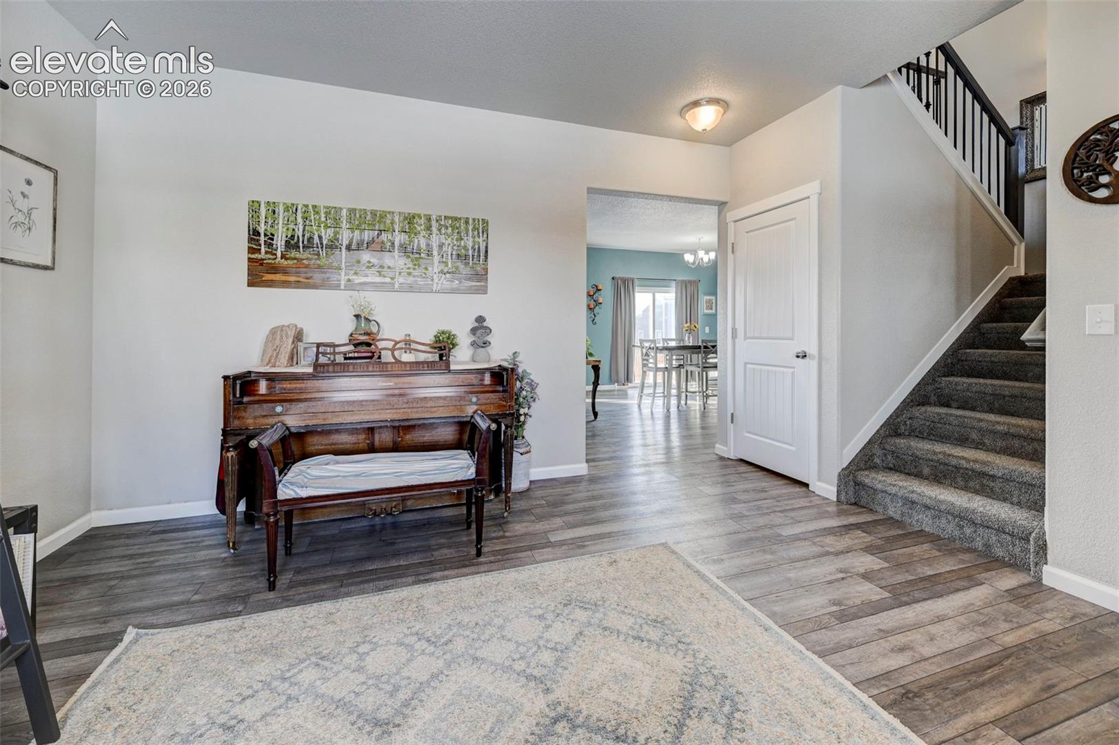 Foyer featuring wood-finish flooring, a staircase with a dark wood handrail, and a panel door