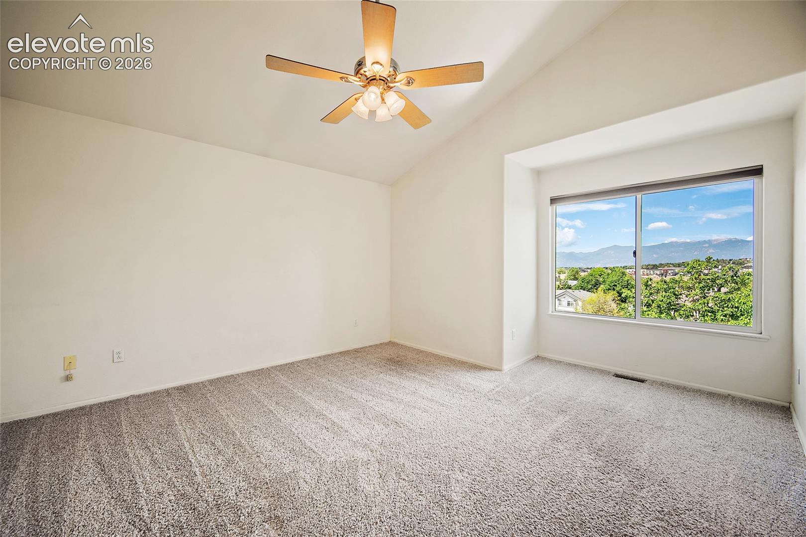 Room featuring a vaulted ceiling with a ceiling fan, neutral wall paint, and gray textured carpeting