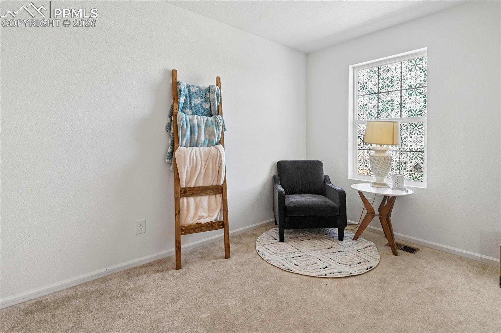 Carpeted room with a patterned window treatment, white baseboards, and light-colored wall paint