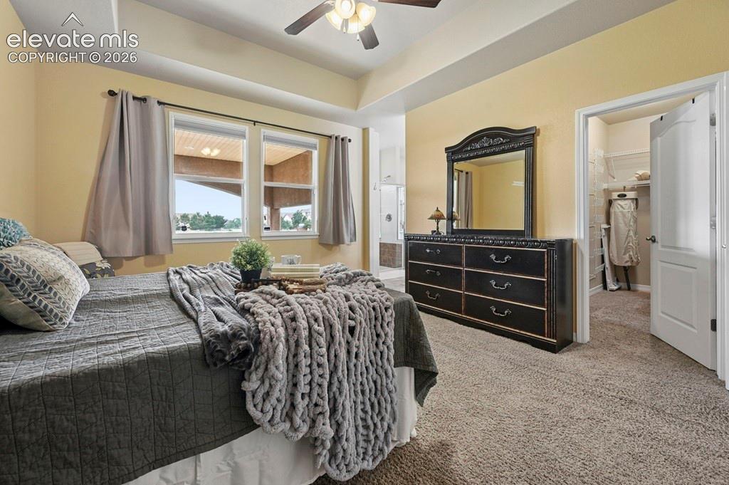 Recessed ceiling with an attached fan, dual windows, and an open doorway leading to an additional space