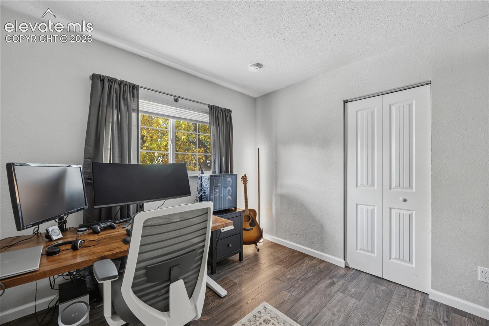 Room featuring wood-finish flooring, a horizontal sliding window, and a white paneled bifold closet door