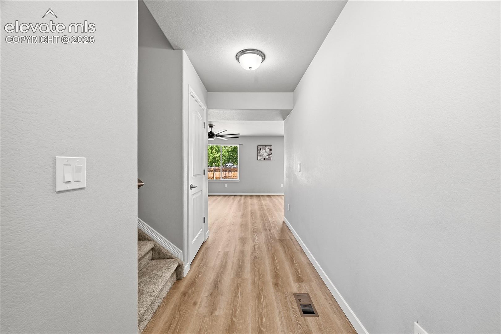 Hallway featuring wood-finish flooring, a ceiling-mounted light fixture, and light gray wall paint