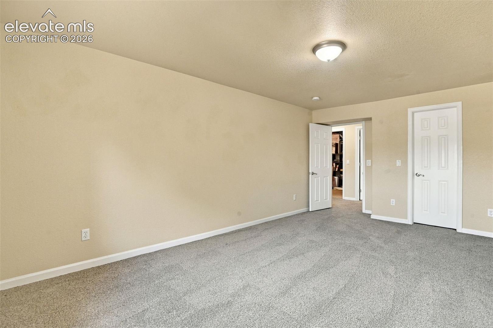 Neutral-toned walls, grey wall-to-wall carpeting, flush-mount dome lighting, and white six-panel interior doors