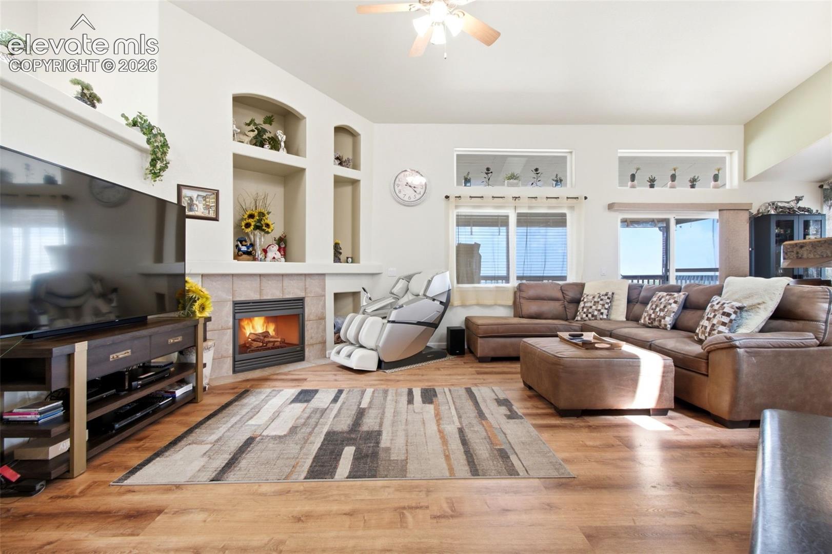 Laminate Wood-finish flooring throughout, featuring a corner gas fireplace with a tile surround and built-in display niches