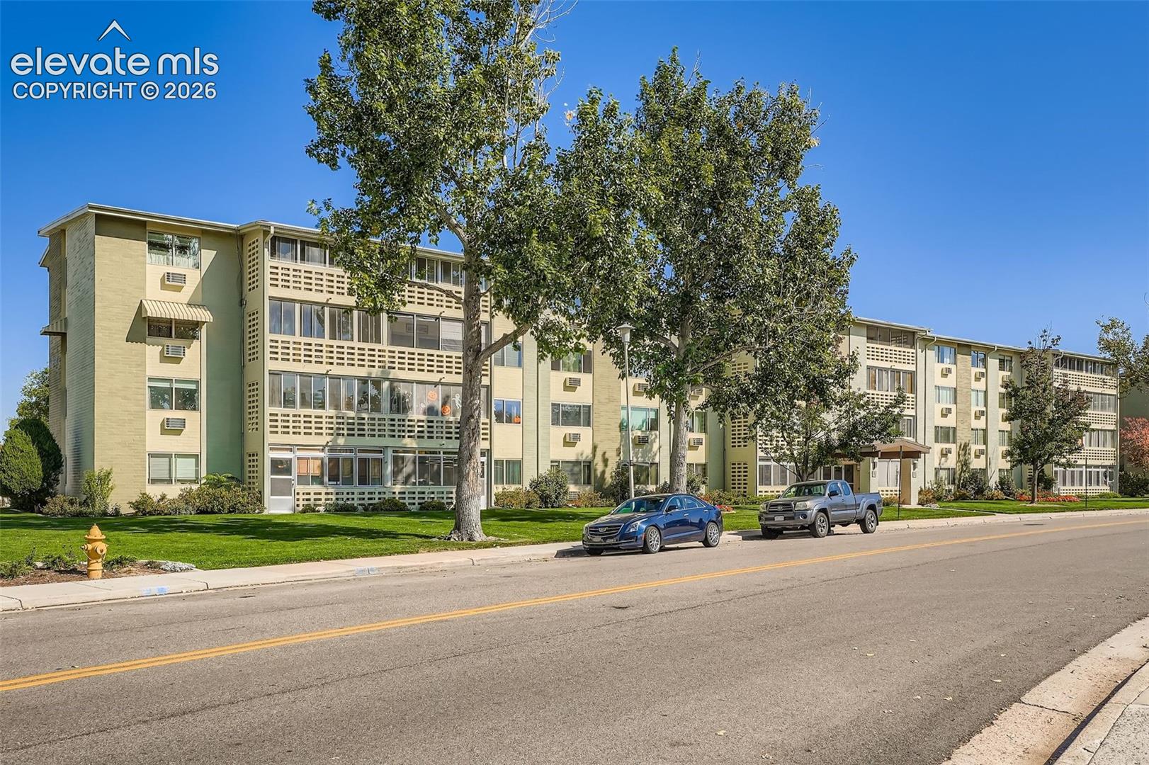 Multi-story residential building featuring a light green exterior, multiple windows, and covered entryways