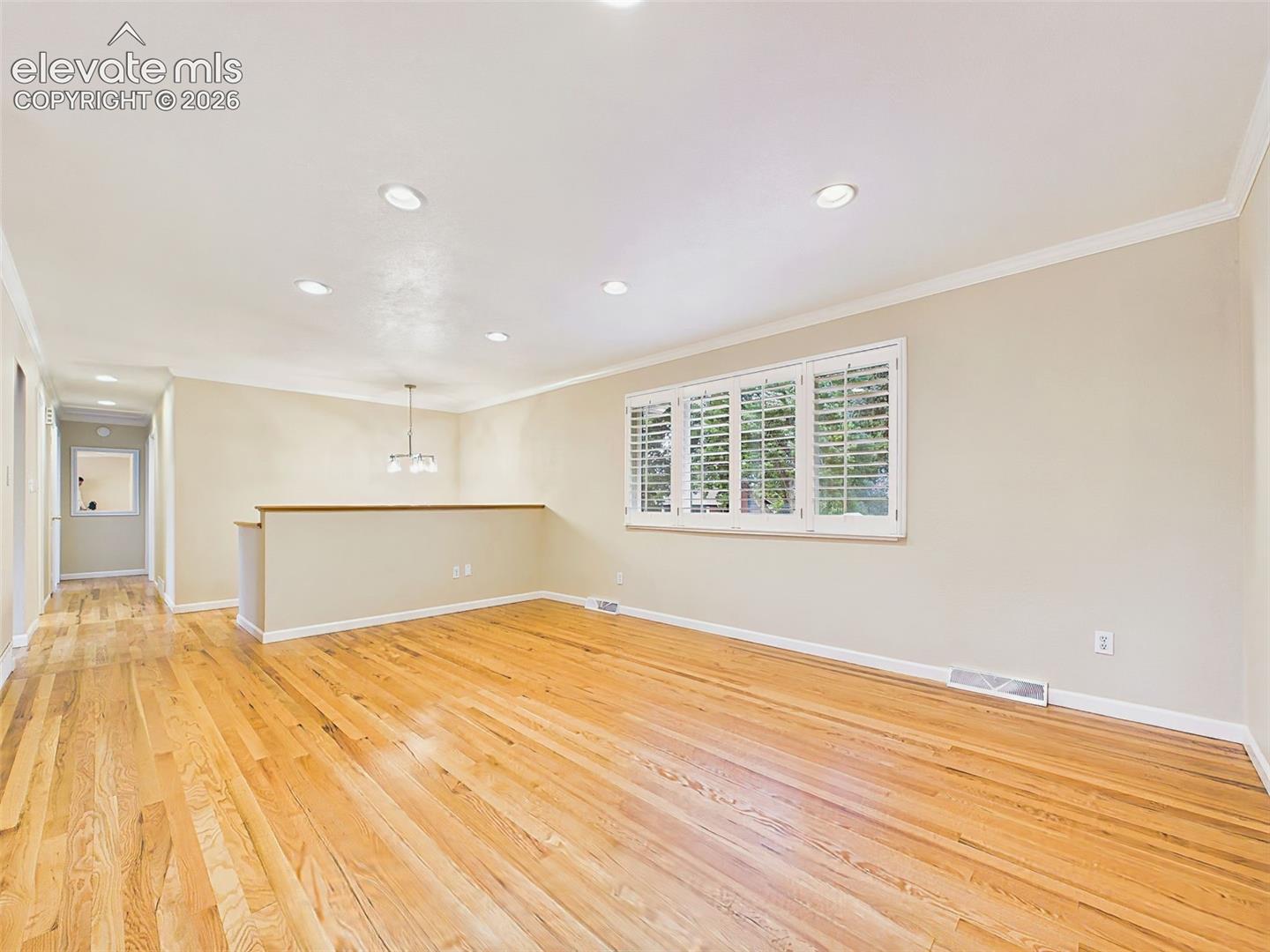 Living Room – Another view of the living room highlights its spacious layout, recessed lighting, and refinished hardwood floors that extend throughout the main living areas.